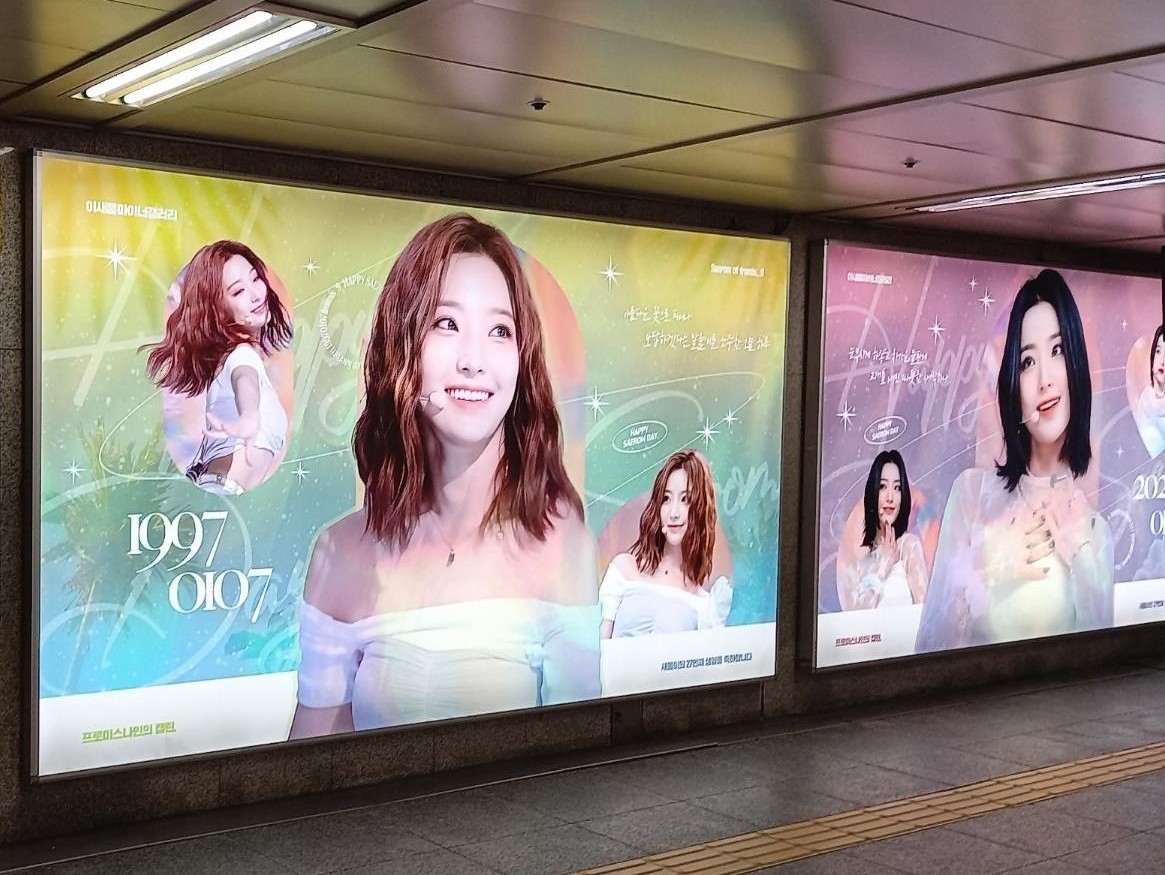 Saerom birthday ad in two large subway lightboxes, a green and yellow panel with the numbers 1997 0107 and a pink and purple panel beside it