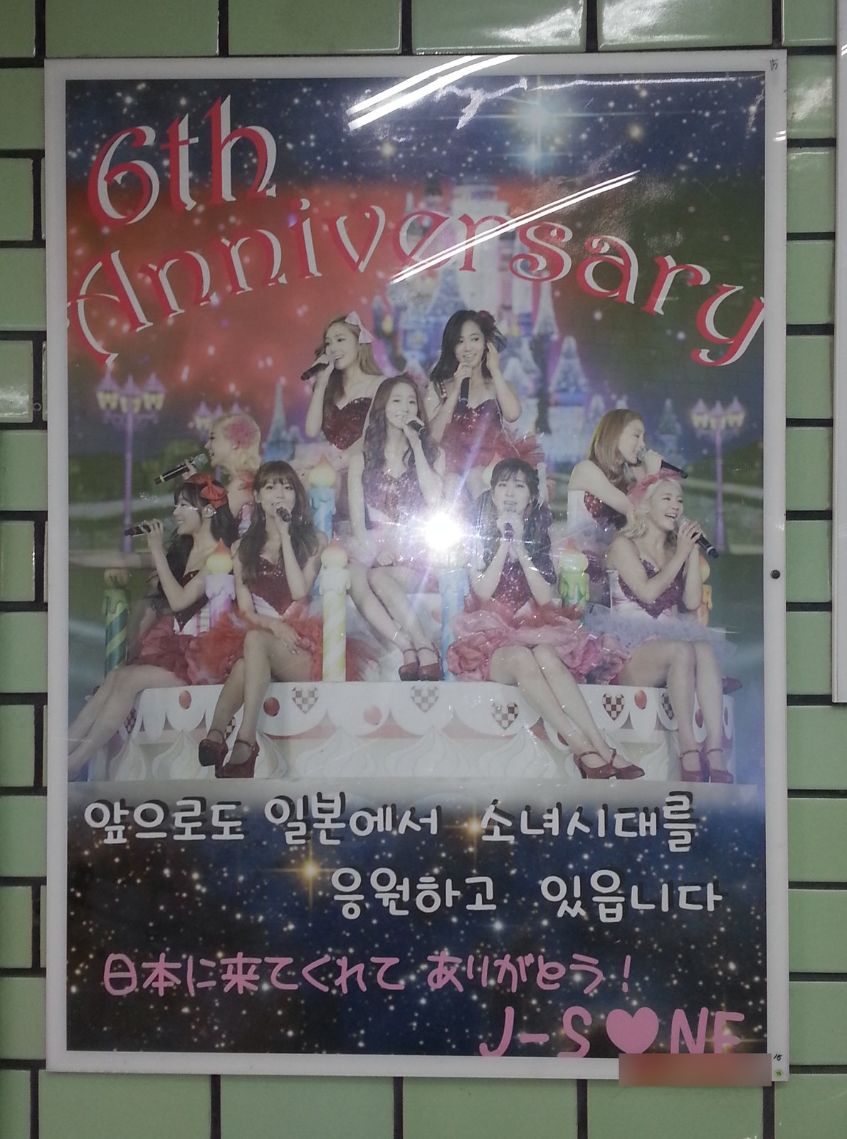 The poster on a green brick-pattern wall in another station