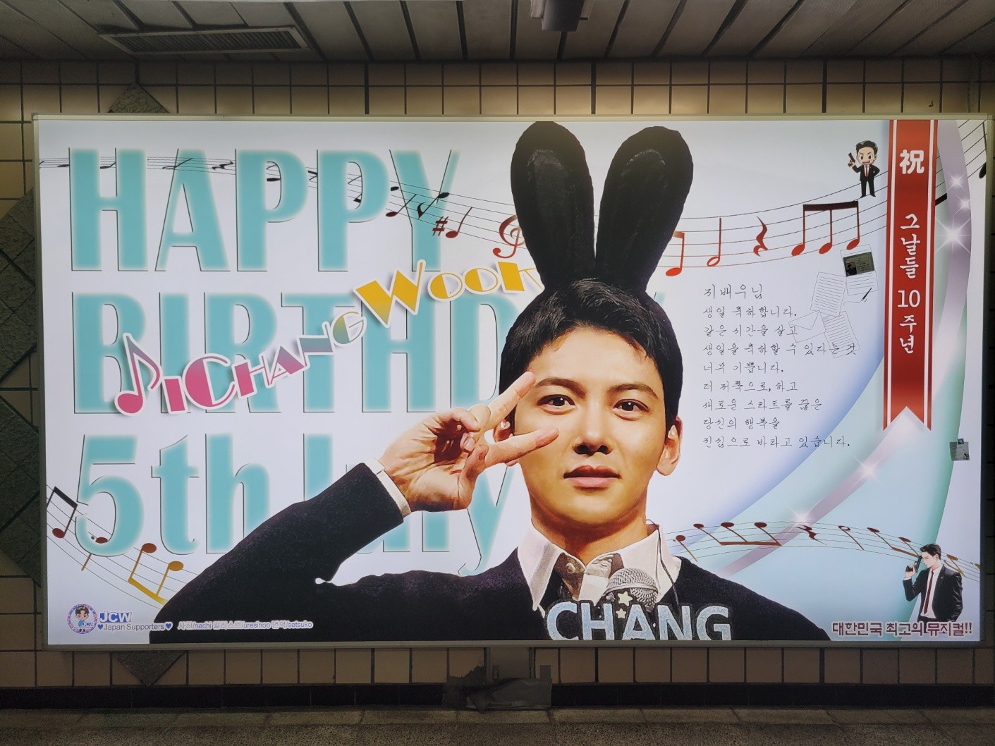 Ji Chang Wook birthday ad on a wide lightbox at Nambu Bus Terminal Station reading HAPPY BIRTHDAY 5th July, with music notes across a white background
