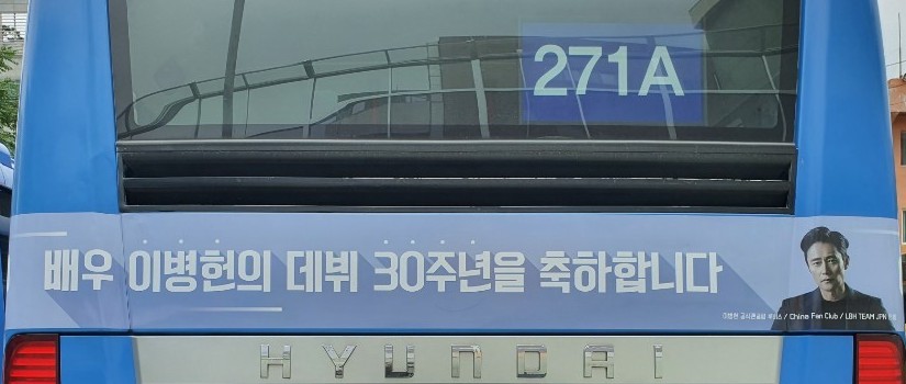 Rear of the bus, number 271A in the window, with a strip ad carrying the anniversary headline in Korean