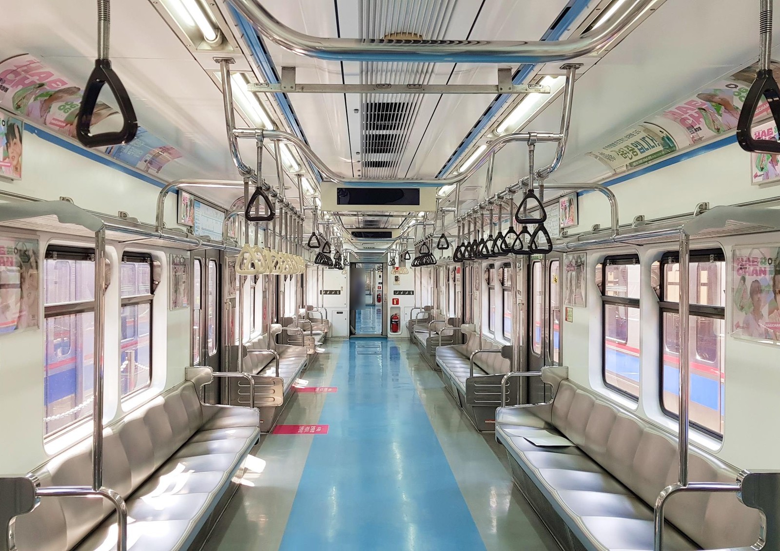 View down an empty subway car with pink Haechan birthday posters in the frames on both sides