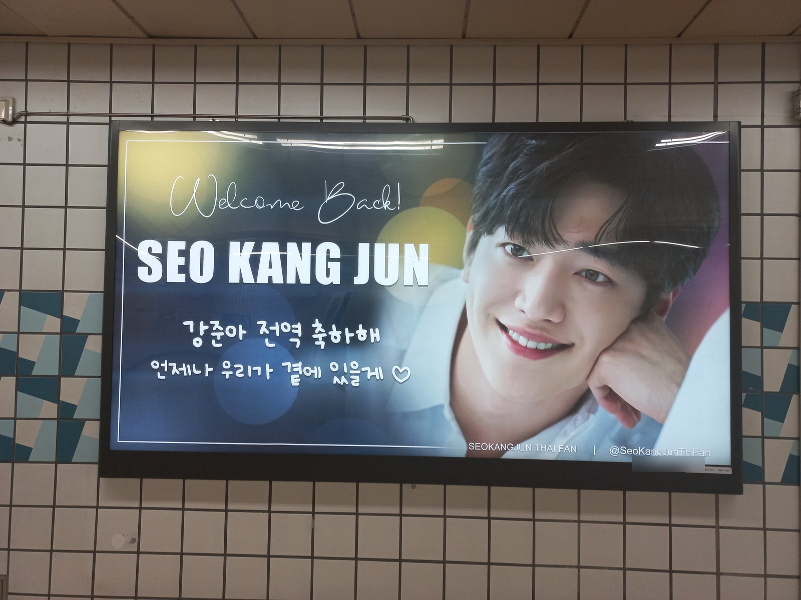 Seo Kang-joon welcome-back fan ad on a lightbox at Hakdong Station, his name in white capitals beside a smiling portrait